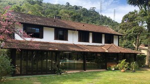 A two-story house with a tiled roof, large glass windows, and a well-maintained lawn. - Kronemhouse Pousada (Petrópolis)