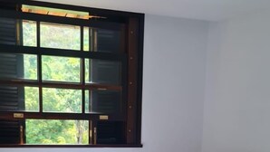 A bedroom with two beds, a window with blinds, and a ceiling light. - Kronemhouse Pousada (Petrópolis)