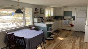 A kitchen with a dining table, chairs, and a view of the outdoors. - Cozy Waterfront Cottage, Henry Cove. Winter Harbor (Winter Harbor)
