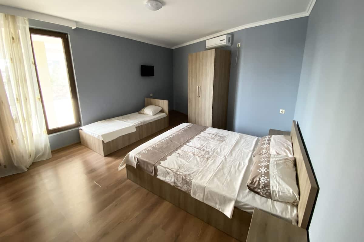 A bedroom with two single beds, a wardrobe, and an air conditioning unit.
