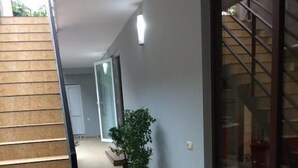 A hallway with a staircase, a potted plant, and a large window. - Hotel Charli (Kobuleti)