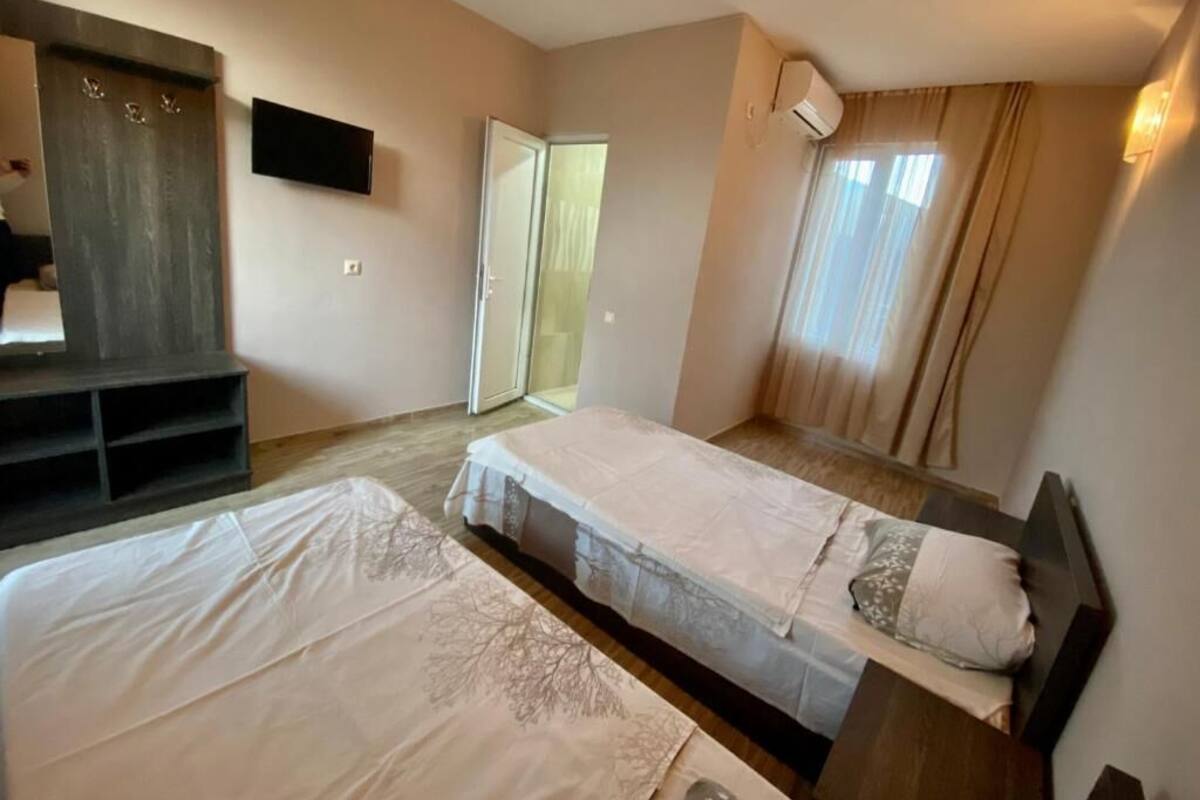 A hotel room with two beds, a TV, a wardrobe, and a sliding door.