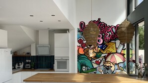 Una cocina moderna con una isla de madera, armarios blancos y un mural colorido en la pared.