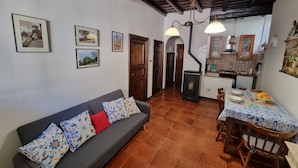 A cozy living room with a sofa, dining table, and kitchen area. - Family apartment near the medieval castle (Bracciano)