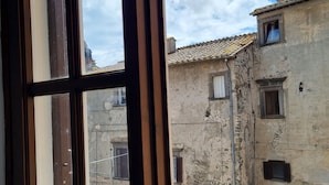 A view through a window of a building with multiple windows and a stone facade. - Family apartment near the medieval castle (Bracciano)