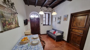 A dining area with a table set for four, a sofa, and a wooden door. - Family apartment near the medieval castle (Bracciano)