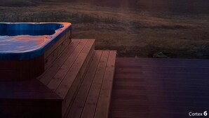 A hot tub on a wooden deck with a view of a sunset over a flat landscape. - Spacious villa in Golden Circle with amazing view & hot tub! (Reykholt)
