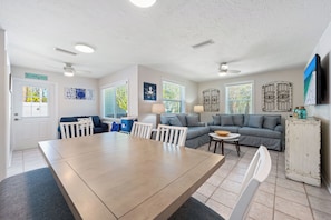 A spacious living area with a dining table, two sofas, and a TV mounted on the wall. - Stunning Pool-side 2 bed/2 Bath With A Quick Walk to Beach!! (Sarasota)