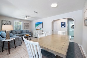 A spacious living room with a large dining table, a sofa, and a TV. - Stunning Pool-side 2 bed/2 Bath With A Quick Walk to Beach!! (Sarasota)