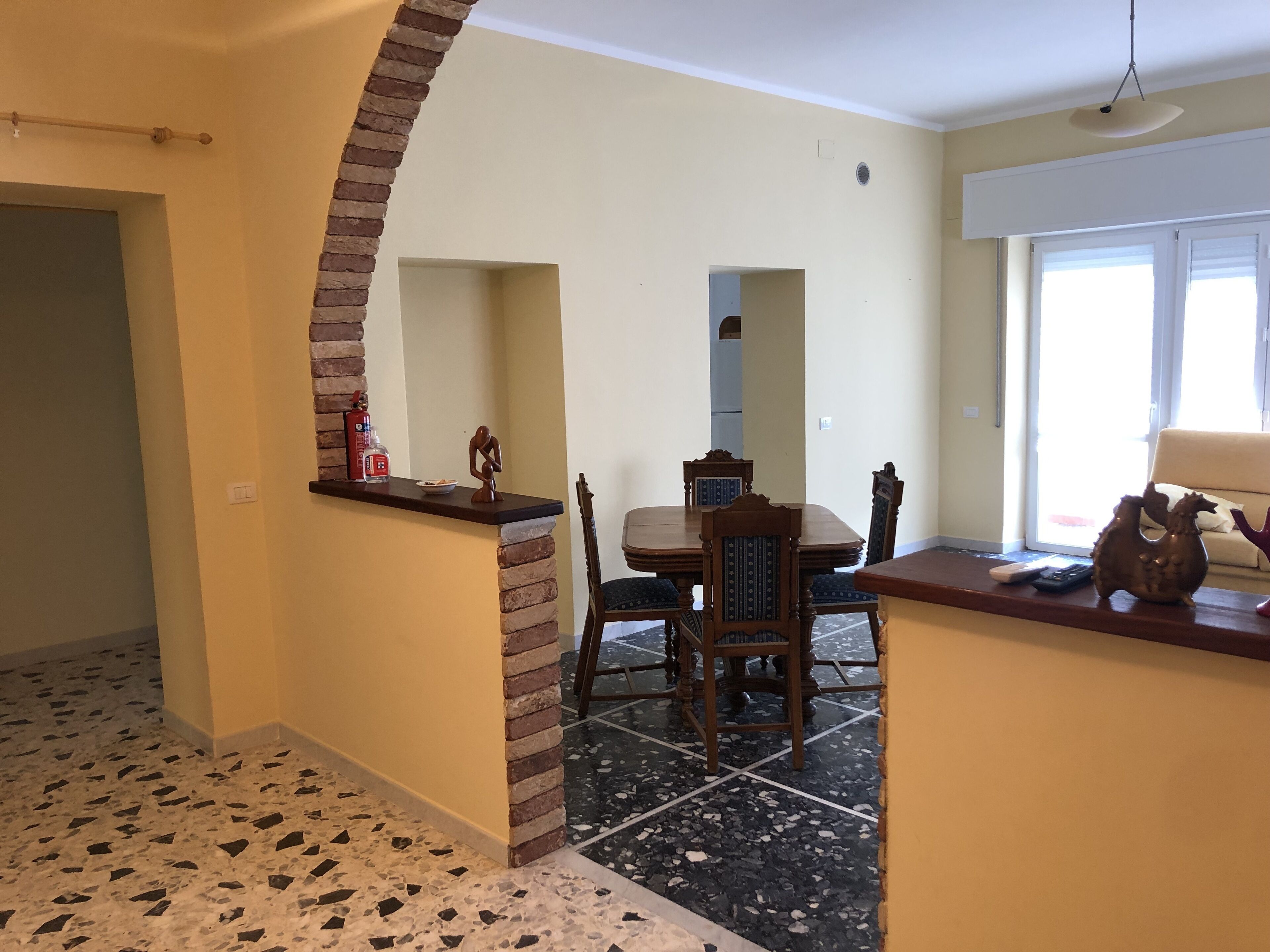 Un espace repas agrémenté d’un mur en briques apparentes, d’un sol carrelé et d’une table à manger avec des chaises.