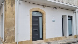 Un edificio con una amplia entrada arqueada, una puerta negra y una pequeña ventana a la derecha.