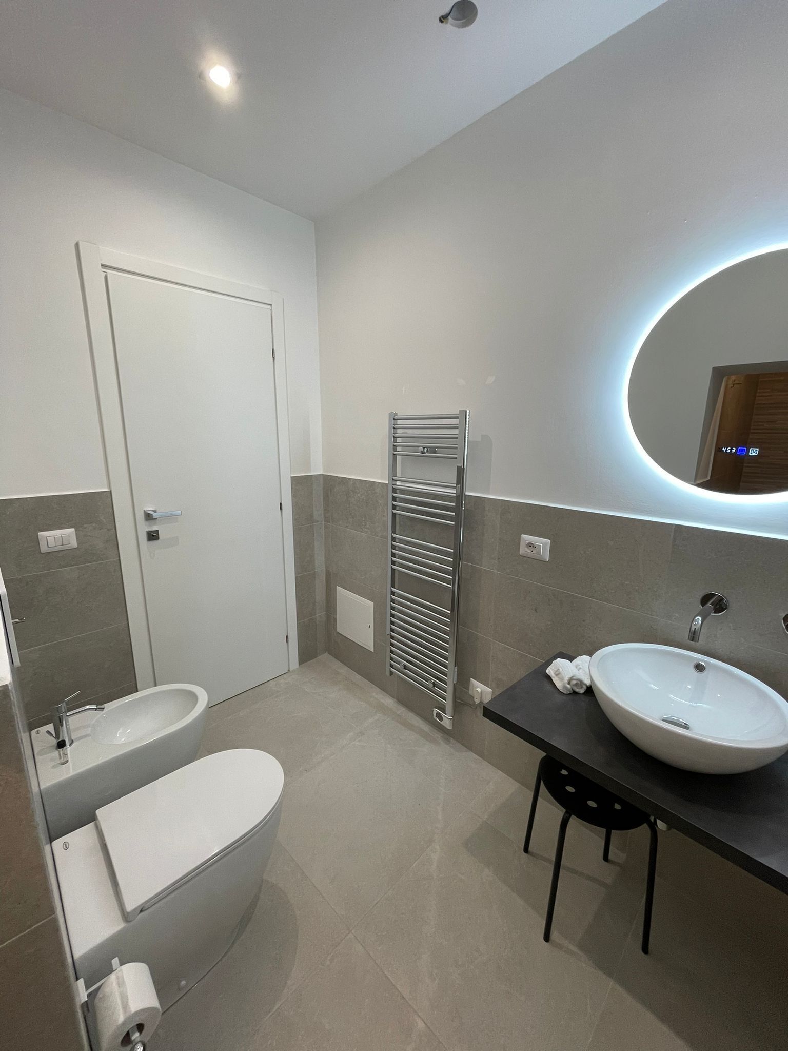 Et moderne badeværelse med toilet, vask og håndklædestang.