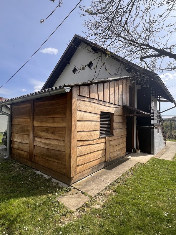 A wooden house with a garage, a small window, and a covered porch. - Auszeit vom Alltag- Sanfter Tourismus in Kroatiens Weinbergen (Leštakovec)