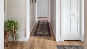 A hallway with wooden flooring, white walls, and a door at the end. - Sweet Shady Lane - Wine Country (Traverse City)
