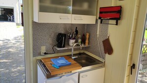 Pieni, käytännöllinen keittiönurkkaus, jossa on pesuallas, kahvinkeitin ja leikkuulauta.