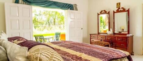 Un dormitorio con cama, cómoda, espejo y puerta abierta que da a un balcón.
