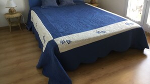 A bed with a blue headboard, two pillows, and a white and blue quilt. There are two nightstands with lamps and a wicker basket on one. - Maison Très Bien Située,dans Quartier Résidentiel.endroit Très Calme ,près Océan (Biscarrosse plage)