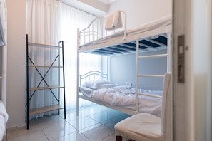 A bunk bed room with a ladder, a chair, and a window with curtains.