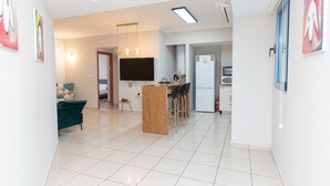 A modern kitchen with a central island, bar stools, and a flat-screen TV. - Mahane Yehuda Market Apartment Jerusalem (Jerusalem)