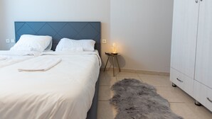 A neatly made bed with white linens, a small bedside table with a lamp, and a furry rug on the floor. - Mahane Yehuda Market Apartment Jerusalem (Jerusalem)
