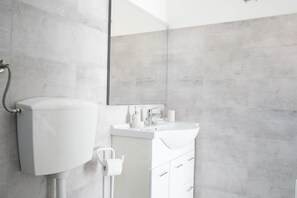 A modern bathroom with a toilet, sink, and mirror. - Resort Leonardo (Melendugno)
