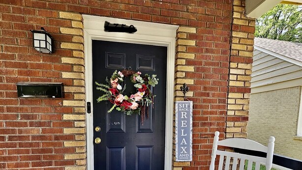 A brick house with a dark blue door, a white bench, a doormat with "hello" on it, and a sign that says "SIT BACK RELAX AND UNWIND". - A cute fully furnished place in Midtown Memphis (Memphis)