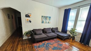 A modern living room with a sectional sofa, a colorful rug, and a large window with curtains. - A cute fully furnished place in Midtown Memphis (Memphis)