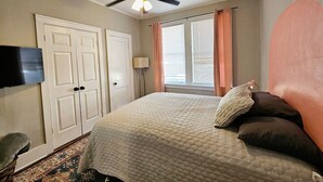 A bedroom with a bed, a ceiling fan, a TV, and a window with curtains. - A cute fully furnished place in Midtown Memphis (Memphis)