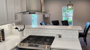 Une cuisine moderne avec des meubles blancs, une cuisinière en acier inoxydable et un grand îlot central doté de sièges.