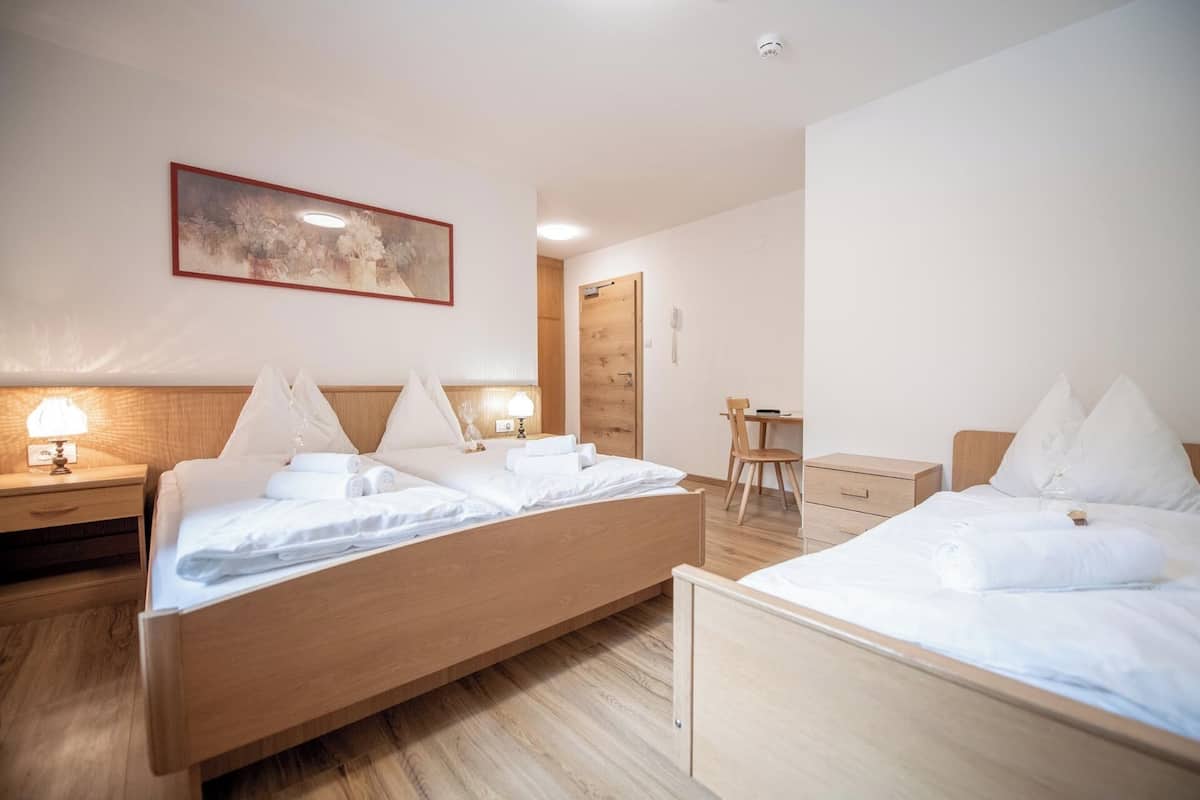 Una habitación de hotel con dos camas, un cabecero de madera, un escritorio y una silla.