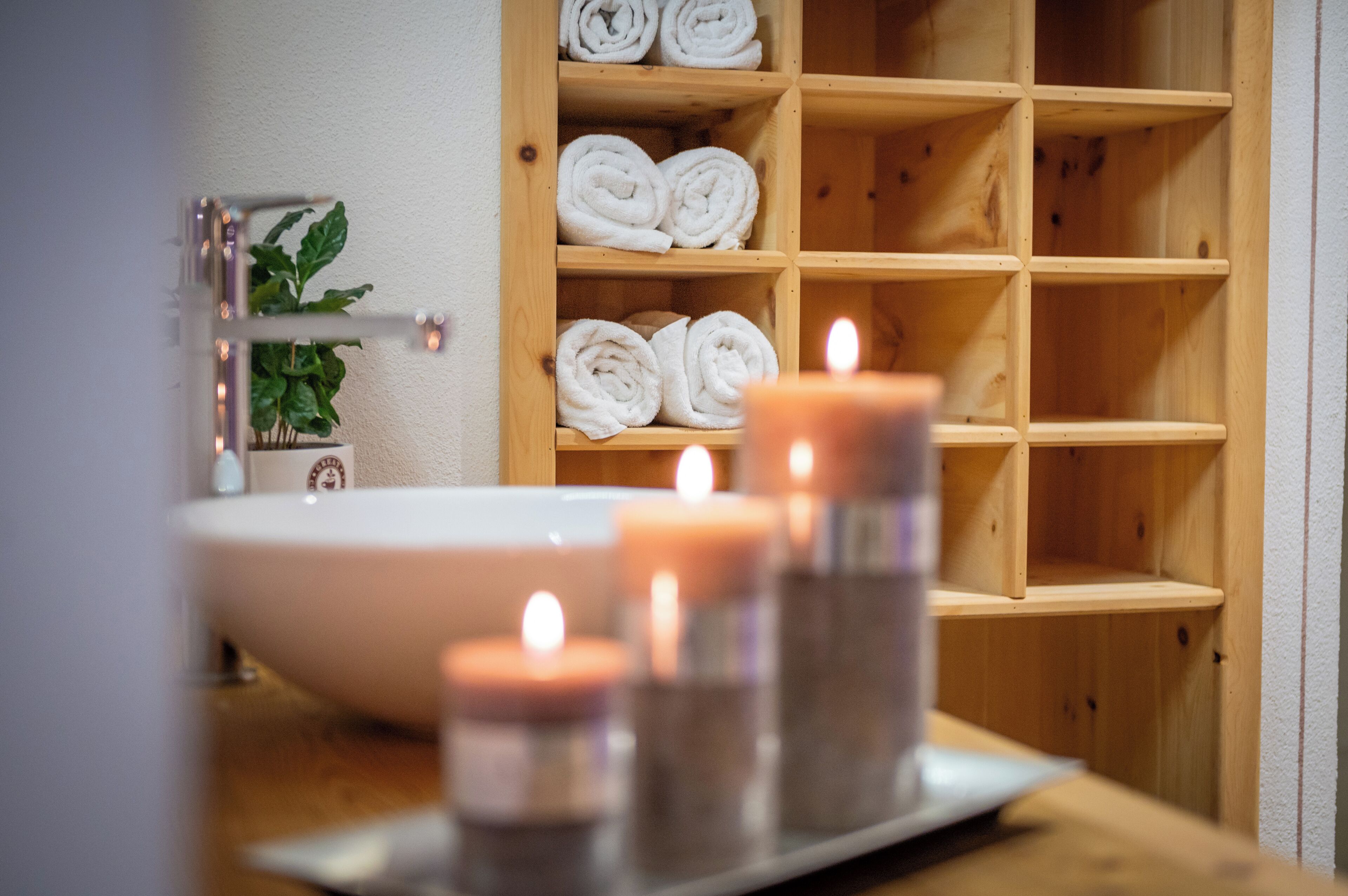 Un baño con repisas de madera, un lavabo y velas.