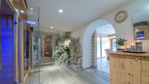 Un interior moderno con una puerta de cristal que da a una habitación, un armario de madera y una pared de piedra con una planta.
