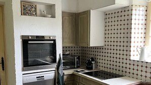 A compact kitchen with a built-in oven, a dishwasher, a microwave, and a sink. - Gîte à la Campagne (Veyrignac)