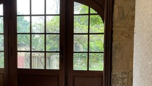 A room with a large window, a bed, and a stone wall. - Gîte à la Campagne (Veyrignac)