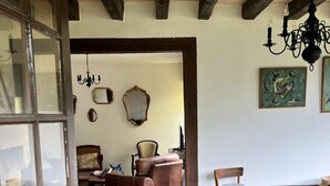 A dining area with a wooden table and chairs, a chandelier, and a checkered floor. - Gîte à la Campagne (Veyrignac)