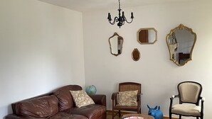 A living room with a brown leather sofa, two armchairs, a wooden coffee table, and a chandelier. - Gîte à la Campagne (Veyrignac)