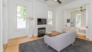 A modern living room with a fireplace, a grey sofa, and a flat-screen TV. - Legend RVA - Modern, Chic, Minimalist (Richmond)