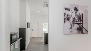 A hallway with a microwave on a glass cabinet, a door, and a black cabinet. - Legend RVA - Modern, Chic, Minimalist (Richmond)
