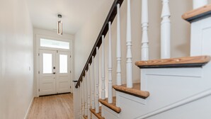A staircase with white balusters and wooden handrails, leading to a door with frosted glass panels. - Legend RVA - Modern, Chic, Minimalist (Richmond)