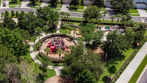 Eine Vogelperspektive eines Parks mit Spielgeräten, Spazierwegen und umgebender Bepflanzung.