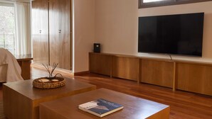 Una sala de estar moderna con un televisor de pantalla plana grande montado en la pared, piso de madera, una mesa de centro con un libro y un armario grande con puertas correderas.
