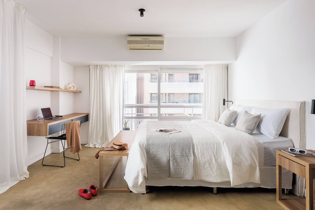 A modern hotel room with a bed, a desk, and a computer.