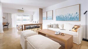 Una sala de estar moderna y bien iluminada, con una mesa de centro de madera, un sofá y una zona de comedor con mesa y sillas.