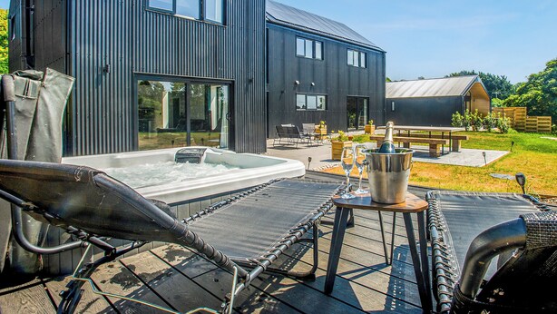 A modern building with a large outdoor hot tub, lounge chairs, and a picnic table. - 5 bedroom accommodation in Marldon, near Paignton (Marldon, near Paignton)