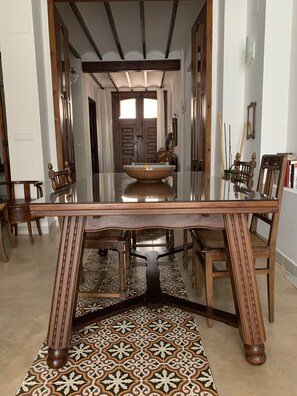 Een eethoek met een tafel met glazen blad, houten stoelen en een vloer met een patroon.