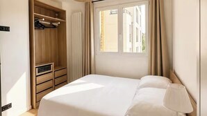 Een slaapkamer met een bed, een bedlampje, een kledingkast en een raam.