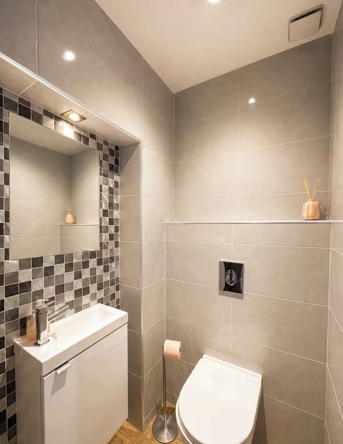 Une salle de bain moderne avec une douche carrelée, un lavabo avec un miroir et des toilettes.