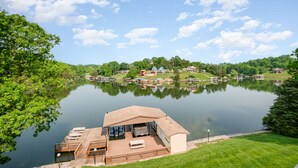 Una propiedad frente al lago con muelle, mobiliario exterior y vistas al lago y la vegetación circundante.