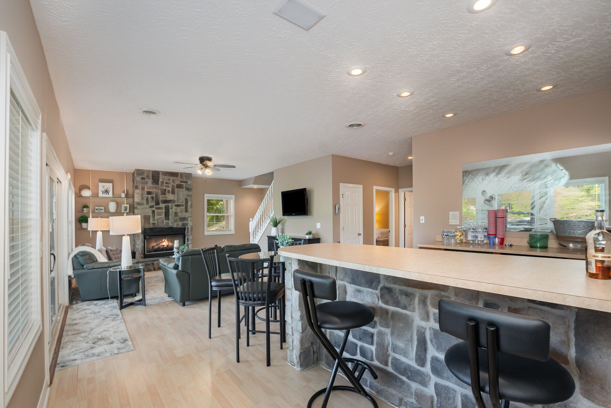 A spacious living area with a stone accent wall, a fireplace, and a bar area with stools.