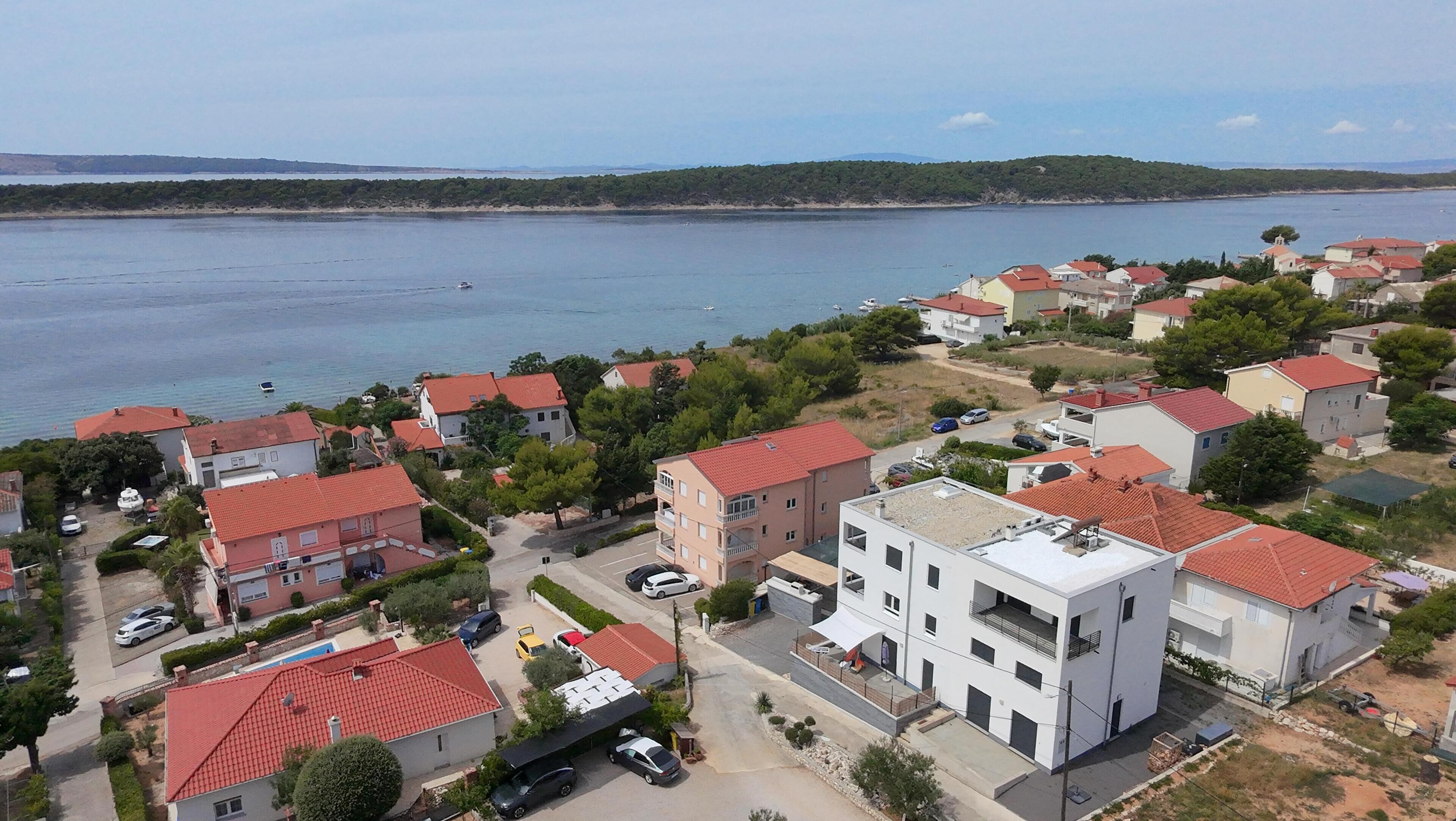 Et kystnært boligområde med huse med røde tegltage, en lysthavn og udsigt til havet.
